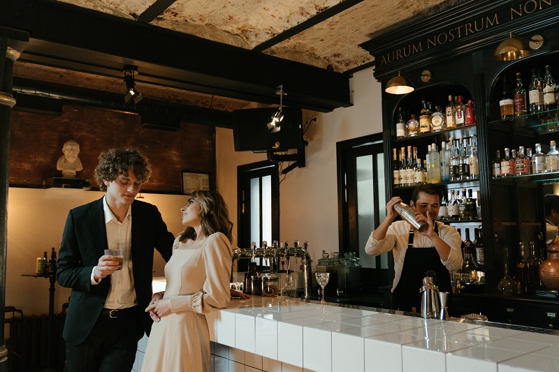 Woman leaning on bar while talking - Dope Uncle