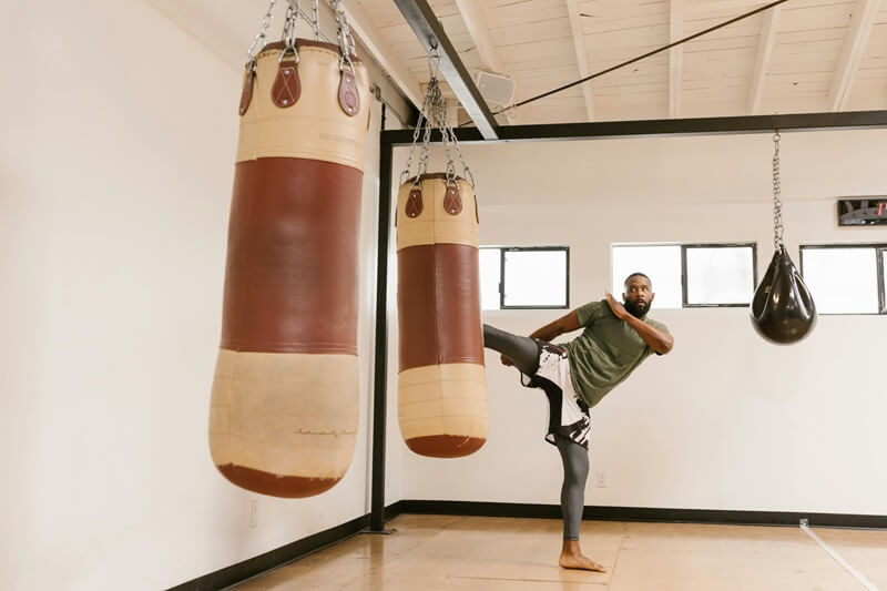 Man kicking punching bag in the gym