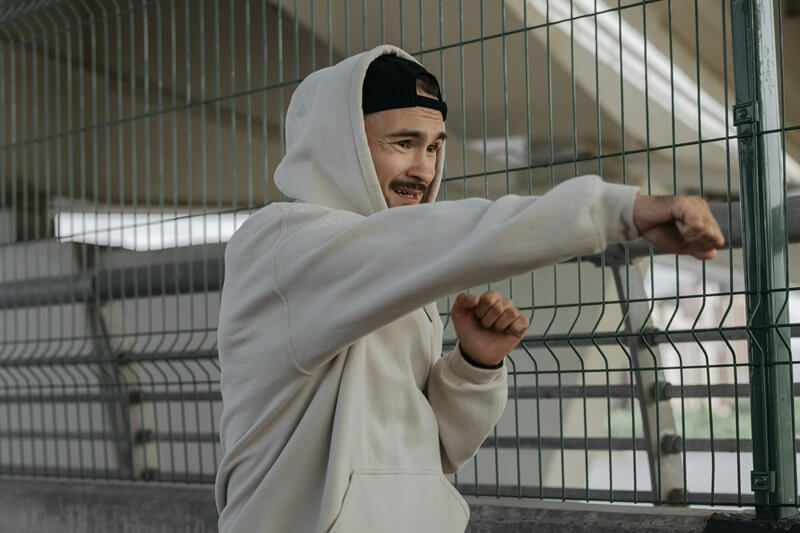 Man with grey hoodie and cap punching the air