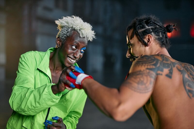 Man with white hair blocking punch from shirtless man